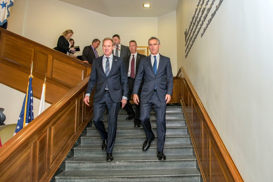 Acting defense secretary and NATO secretary general walk down stairs at the Pentagon.