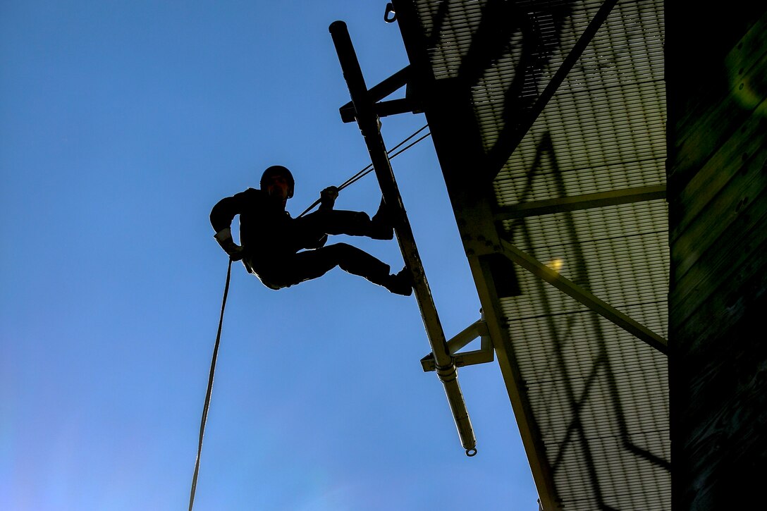 A Marine rappels down a wall.