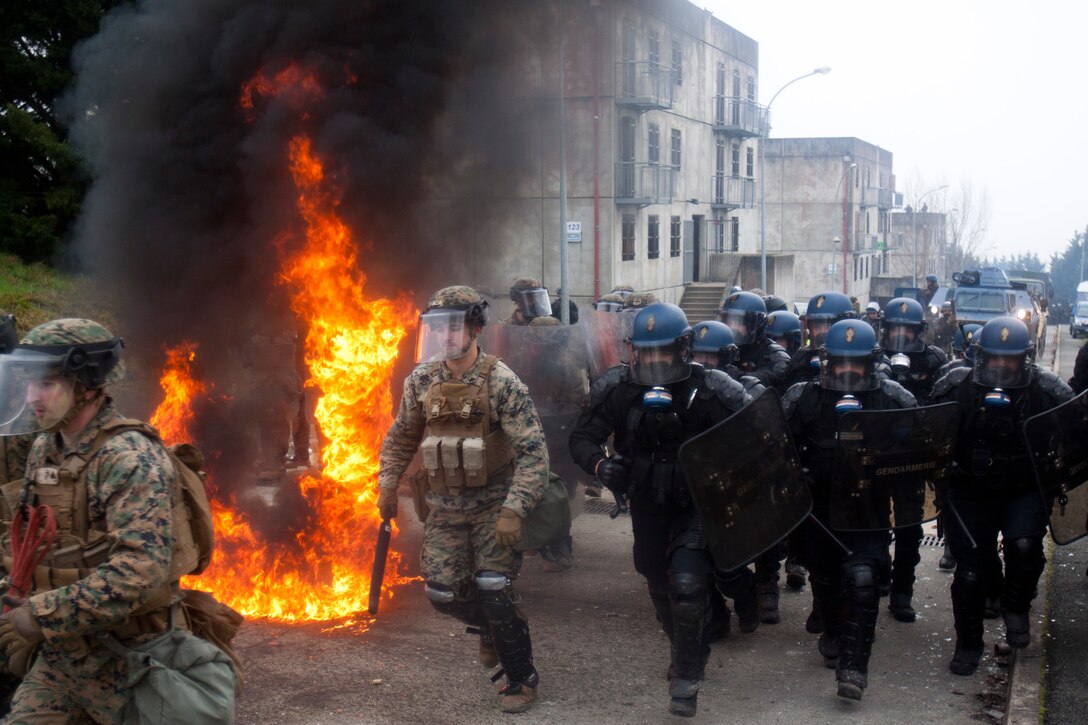 U.S. Marines with Special Purpose Marine Air-Ground Task Force-Crisis Response-Africa bound past flames from a Molotov cocktail to retrieve an injured mock rioter during a simulated U.S. embassy reinforcement exercise at the National Gendarmerie Tactical Training Center in Saint-Astier, France, Jan. 18, 2019. SPMAGTF-CR-AF is a rotational force deployed to conduct crisis-response and theater-security operations in Europe and Africa. (U.S. Marine Corps photo by 2nd Lt. Taylor Cox)