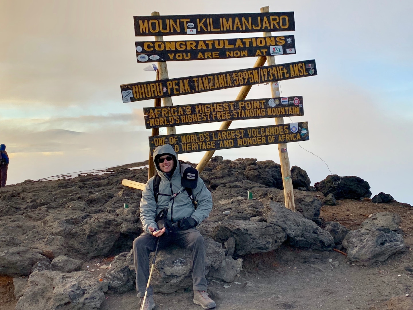 Jeff Crow, material planner in the Defense Logistics Agency Troop Support’s Industrial Hardware supply chain, rests on a rock under the sign that marks his accomplishment in climbing Tanzania’s Mount Kilimanjaro during a trip in December 2018.