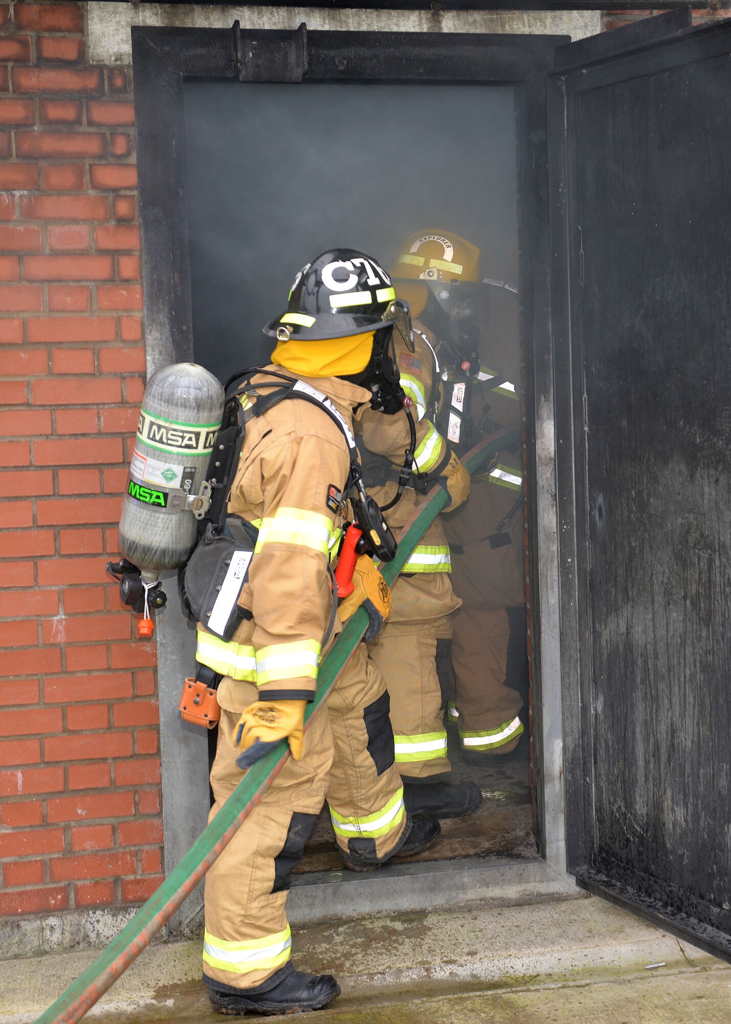 U.S. Air Force Chief Master Sgt. Kristina Rogers, left, 100th Air Refueling Wing command chief, prepares to advance into a live fire with Airman 1st Class Adam Strizak, 100th Civil Engineer Squadron firefighter, and Lead Firefighter Simon Evans, crew manager, as part of a training scenario at RAF Mildenhall, England, Jan. 24, 2019. The 100th ARW command chief participated in the training, performed semi-annually, to get an idea of what the RAF Mildenhall firefighters go through to keep up-to-date in their fundamental skills. The firefighters regularly conduct various types of live-fire training to mitigate hazards and lessen harmful impacts on life, property and the environment. (U.S. Air Force photo by Karen Abeyasekere)