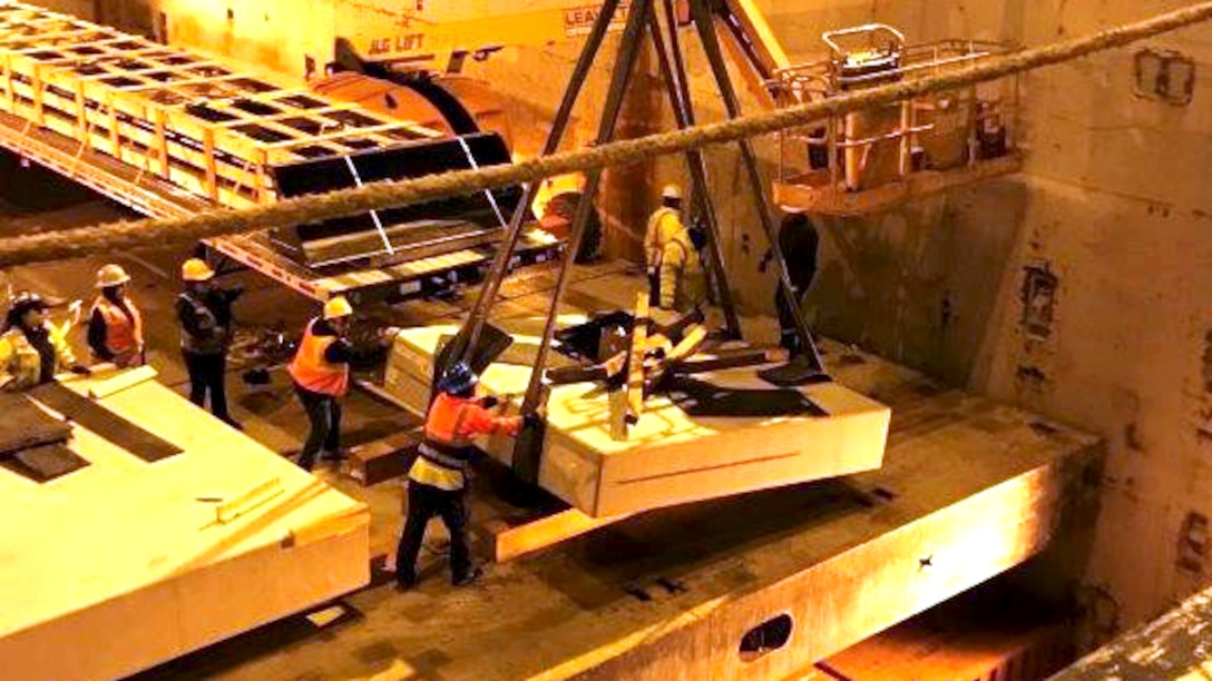 Workers in safety gear guide supplies on a crane