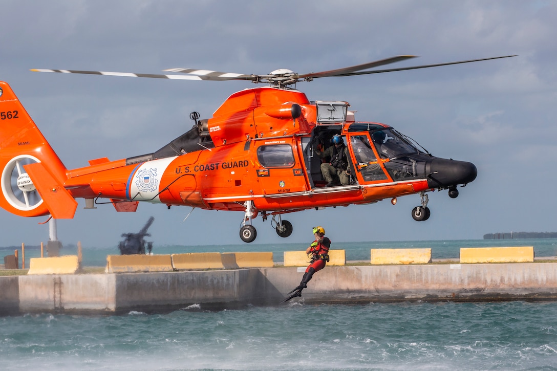 A Coast Guard Air Station Miami rescue swimmer jumps out of a MH-65D Dolphin helicopter to assist 514th Air Mobility Wing Reserve Citizen Airmen during water survival training at Naval Air Station Key West's Truman Harbor, Key West, Fla., Nov. 16, 2018.