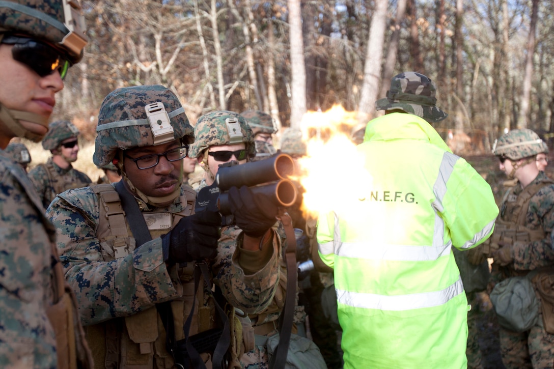 A Marine fires a small weapon, which emits a burst of flame.