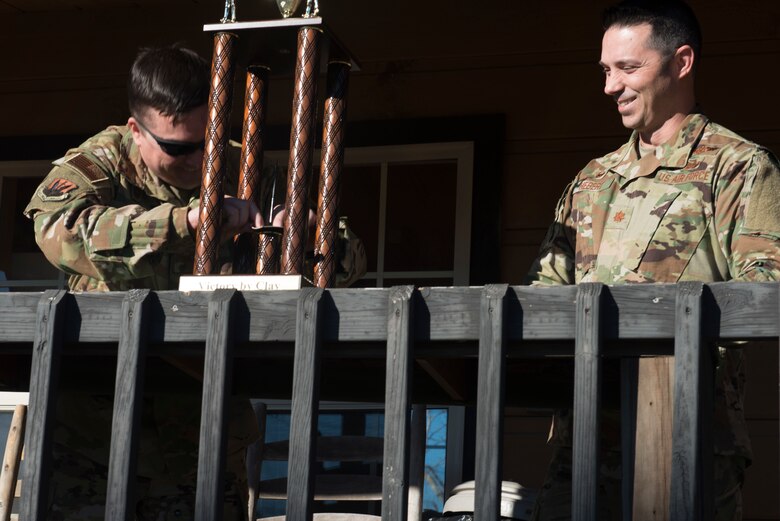 U.S. Air Force Lt. Col. Travis Norton, 25th Attack Group commander, left, puts his squadron patch on a trophy, symbolizing defeat, while Maj. Darryl Hebert, 20th Force Support Squadron commander smiles, at Skeet and Trap range, Shaw Air Force Base, S.C., Jan. 25.