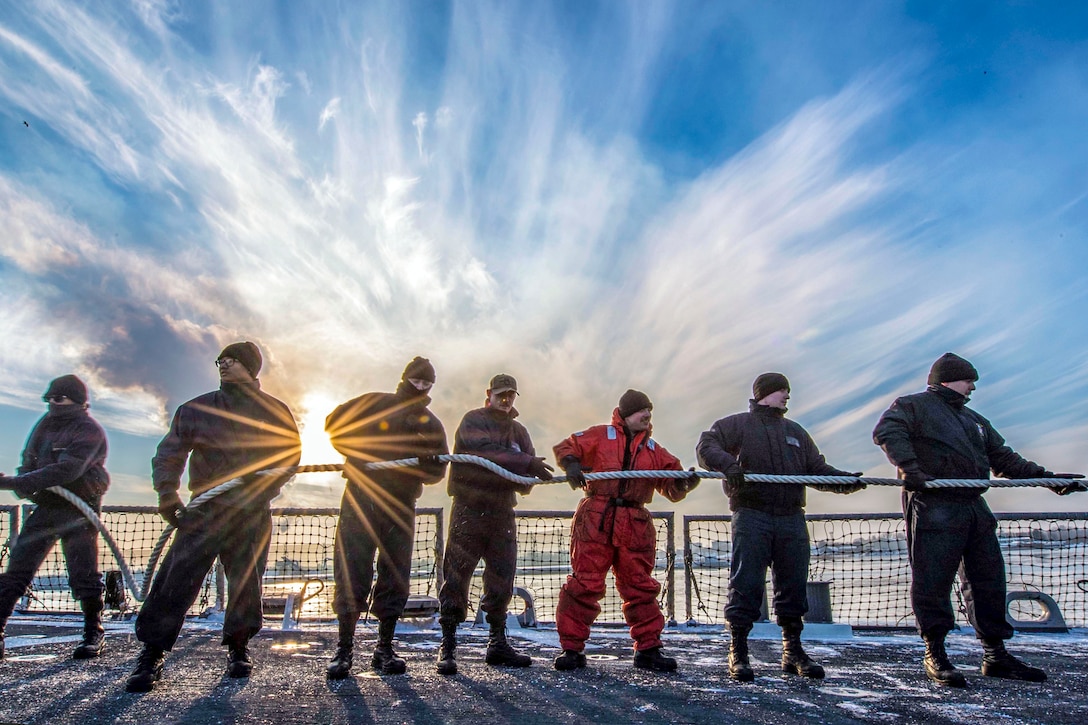 Sailors stand in line to collect and store mooring lines.