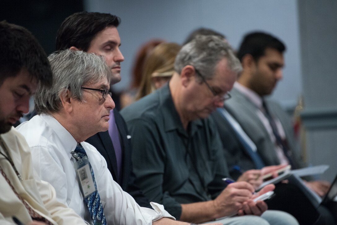 Reporters take notes at a news conference