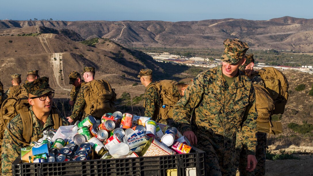 Marines with 1st Radio Battalion, I Marine Expeditionary Force Information Group, transport canned goods during a hike for those in need at Camp Pendleton, Calif., November 16, 2018.