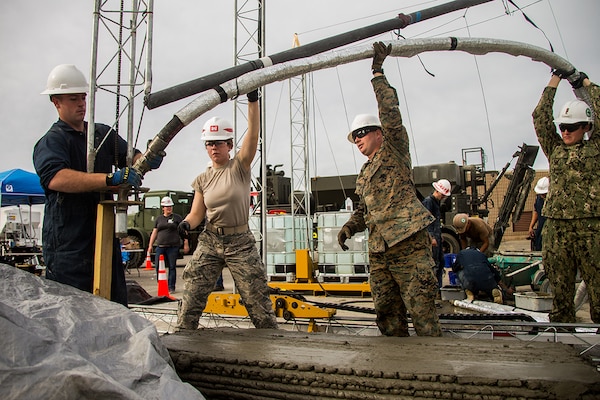 Marines with 7th Engineer Support Battalion and Sailors with Naval Mobile Construction Battalion 5 attach hose onto 3D concrete printer during 3D Concrete Printing exercise at Camp Pendleton, California, December 9, 2018 (U.S. Marine Corps/Betzabeth Y. Galvan)