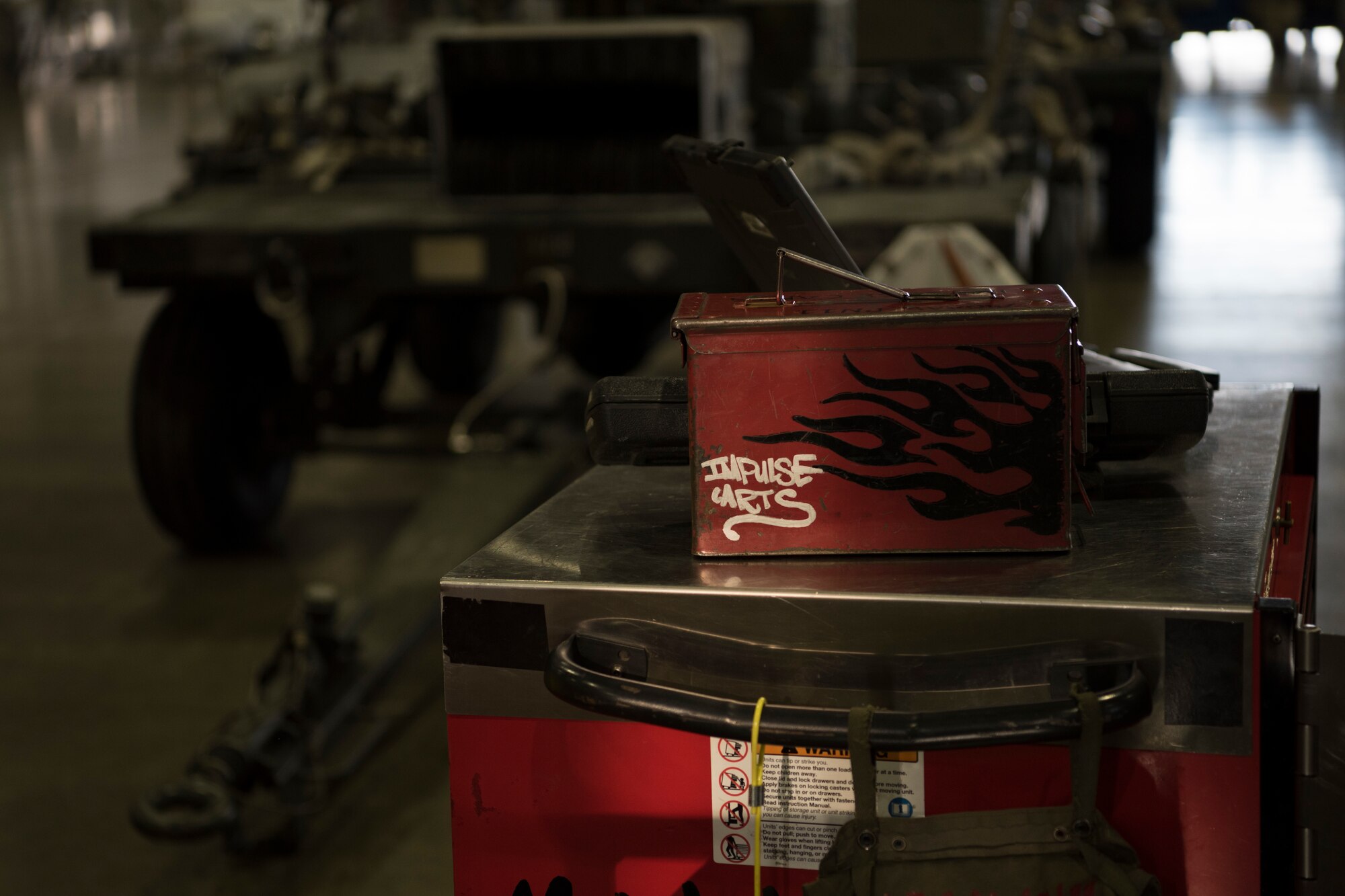 A box with the words “Impulse Carts” sits on a work station during the fourth quarter weapons load competition at Misawa Air Base, Japan, Jan. 18, 2019. Airmen use various tools and equipment are used during this competition to complete the mission of arming an F-16 Fighting Falcon while racing against the clock and an opposing team. This event aids in enhancing Airmen’s readiness, performance and technical abilities.  (U.S. Air Force photo by Airman 1st Class Collette Brooks)