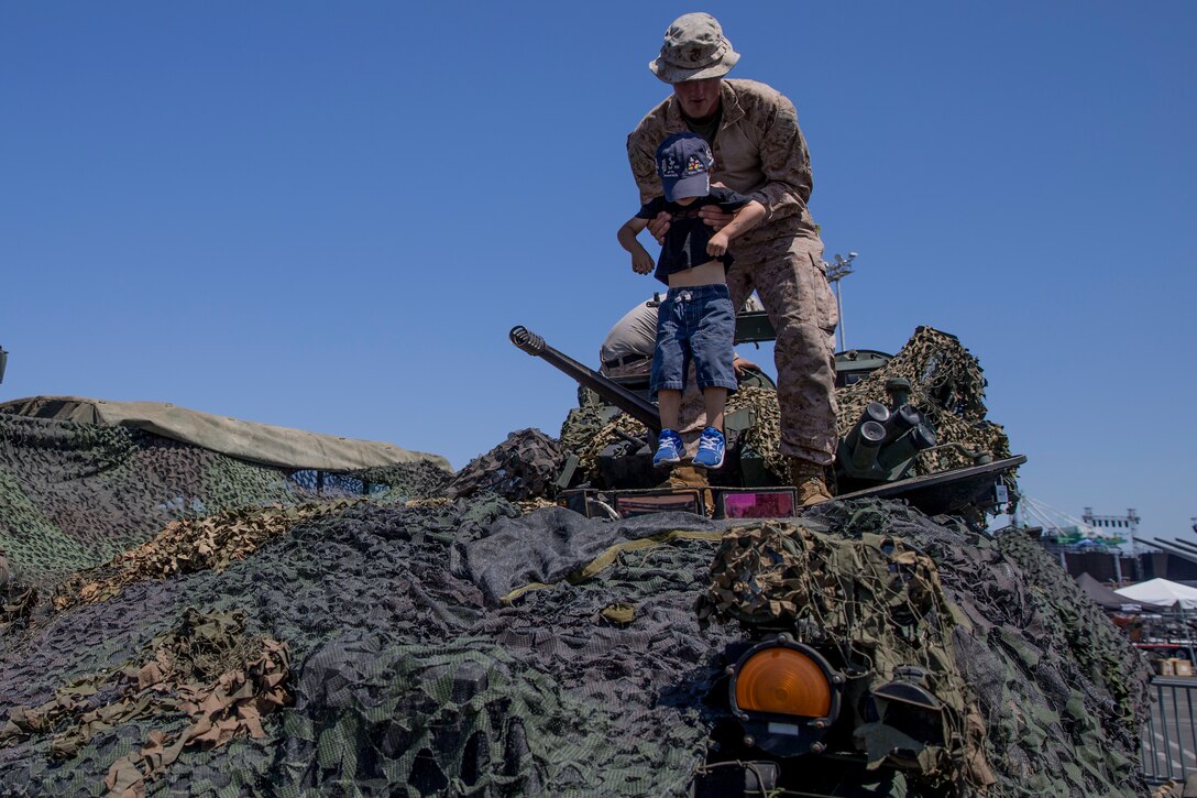 U.S. Marine Corps 2nd Lieutenant Timothy Cottell, a platoon commander with 1st Light Armored Reconnaissance Battalion, 1st Marine Division, assists an young attendee into a Light Armored Vehicle during Los Angeles Fleet Week, Aug. 31, 2018