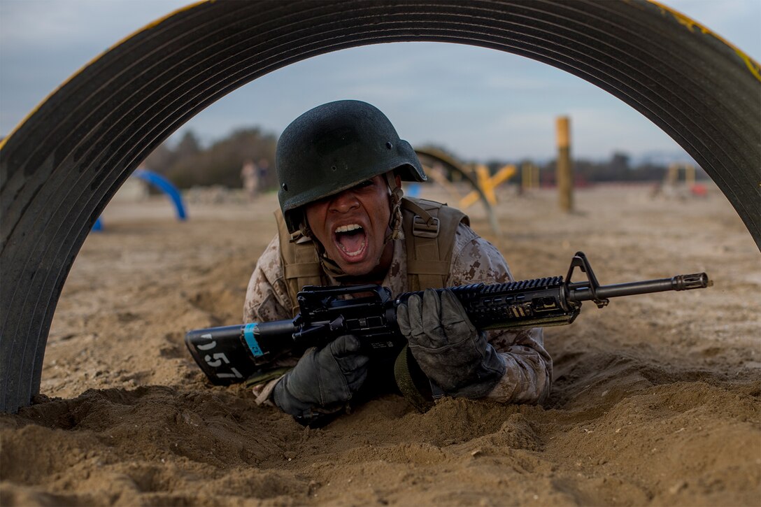 A Marine Corps recruit crawls during a bayonet assault course.