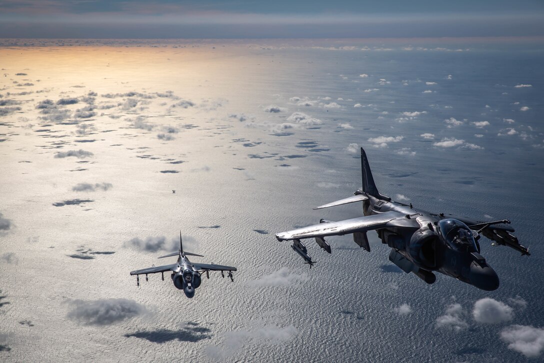 Two jets fly above clouds.