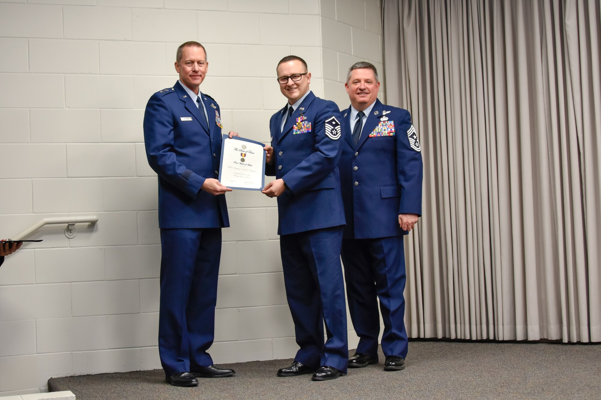 Master Sgt. Neil Robertson, 136th Maintenance Squadron first sergeant, receives a certificate and coin for his achievements from Maj. Gen. David McMinn, commander of the Texas Air National Guard, and Chief Master Sgt. Christopher Castle, command chief of the TANG, during the Outstanding Airman of the Year award ceremony January 13, 2019 at Camp Mabry in Austin, Texas. (U.S. Air National Guard photo by Tech. Sgt. Katy Whitt)