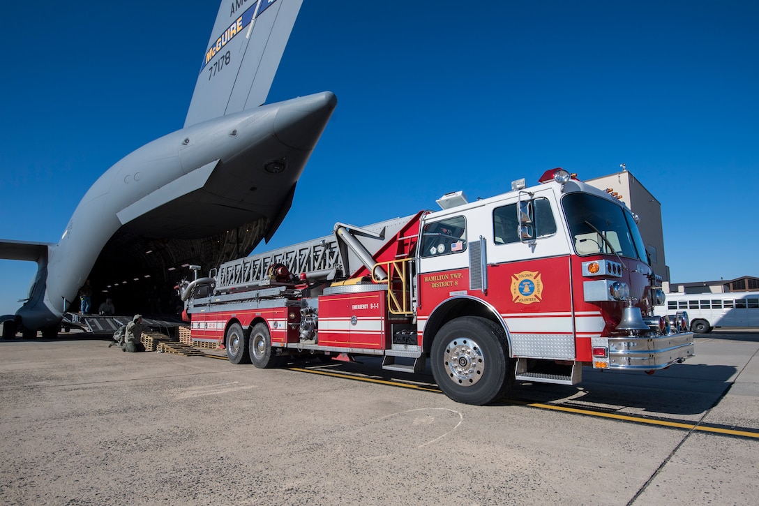 U.S. Airmen with the 305th Aerial Port Squadron and 732nd Airlift Squadron, guide a fire truck onto a C-17 on Joint Base Mcguire-Dix-Lakehurst, N.J., Jan. 31, 2019.