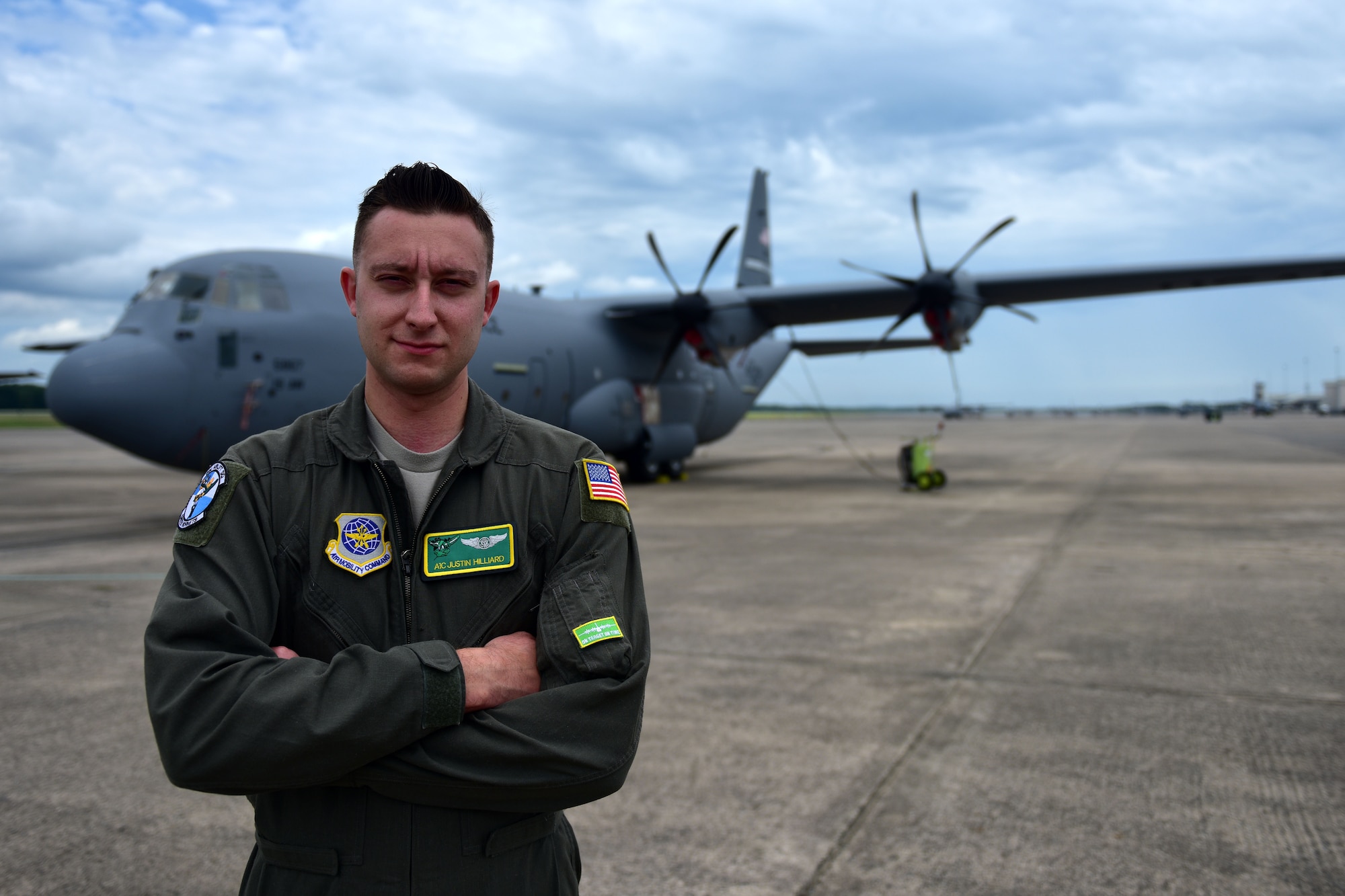 A man wearing a flight suit stands in front of a C-130J.