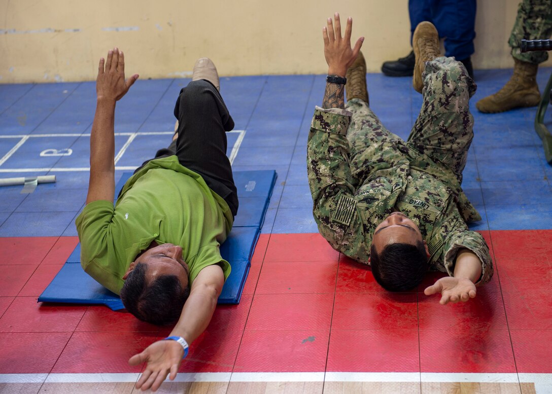 A doctor demonstrates a physical therapy exercise for a patient.