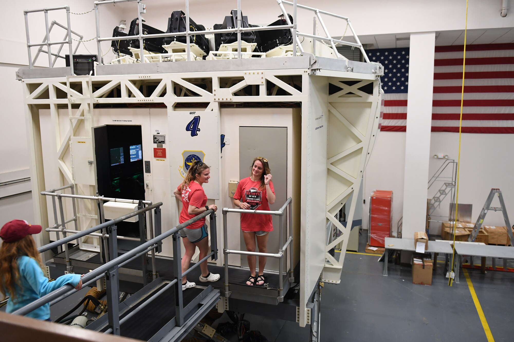 Children walk out onto a C-130J flight simulator.