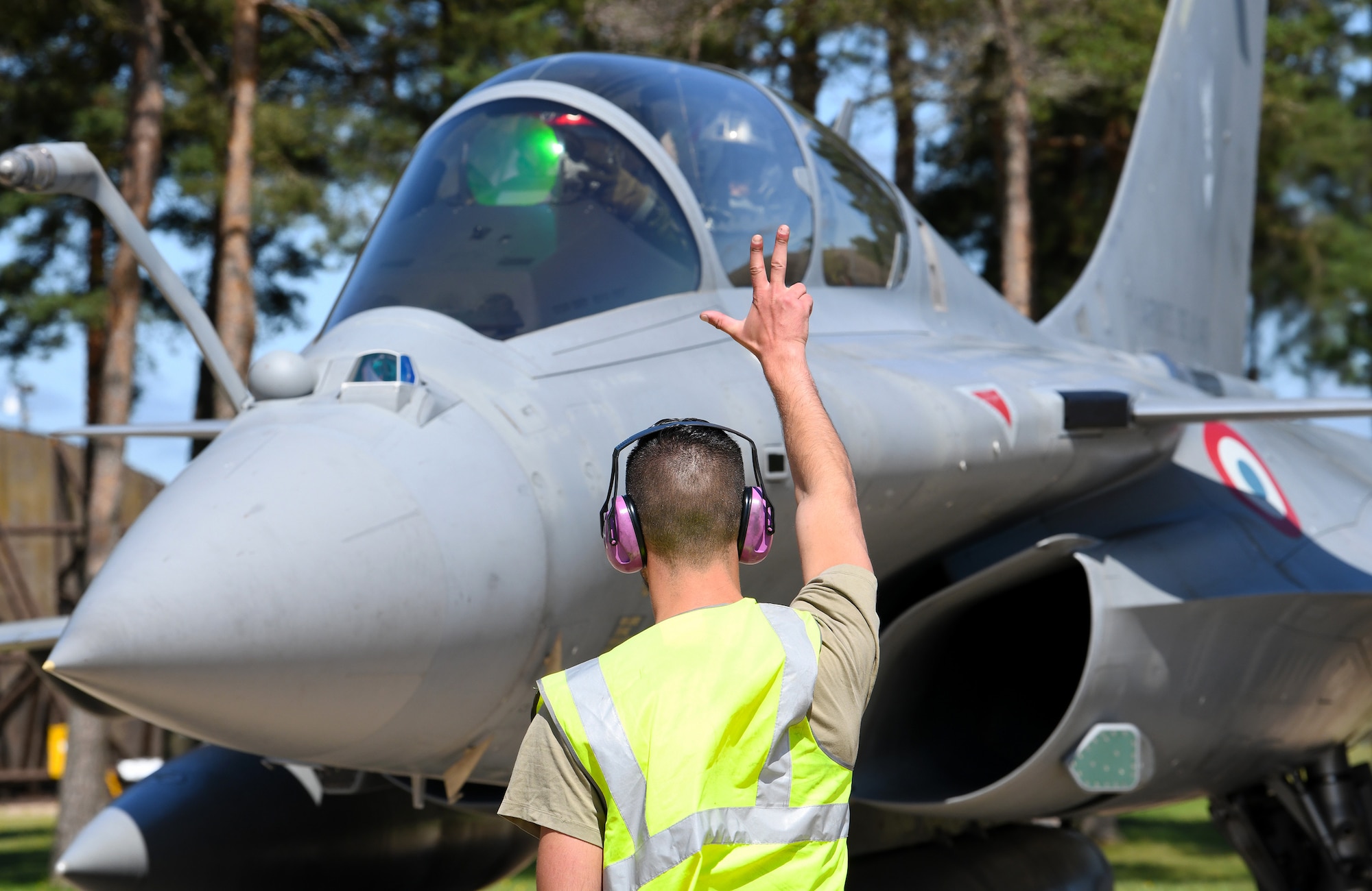 A French Air Force maintainer signals a Rafale pilot during exercise Point Blank 19-2 at Royal Air Force Lakenheath, England, June 17, 2019. During this trilateral exercise, participating air forces are enhancing professional relationships and improving overall coordination with allies and partner militaries during times of crisis. (U.S. Air Force photo by Staff Sgt. Alex Fox Echols III/Released)