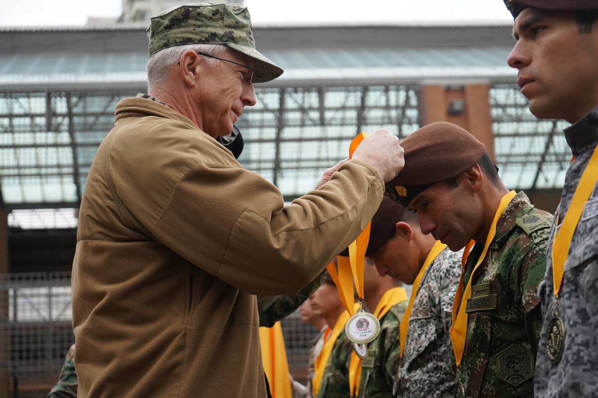 Adm. Craig S. Faller, places a first place ribbon around a Colombian service member.