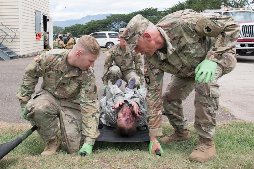 U.S. Army medics from Joint Task Force - Bravo Medical Element transport a burn victim to a casualty collection point during a joint training exercise, June 26, 2019, at Soto Cano Air Base, Honduras. Members from Joint Task Force – Bravo’s Medical Element, 612th Air Base Squadron firefighters and 480th Military Police Company worked together to accomplish goals during the training event. The event involved the firefighters entering a smoke-filled building to recover burn casualties while the Medical Element performed triage at the scene. The 480TH MPC members provided a cordon of the area and kept rioting personnel from entering the scene. (U.S. Air Force photo by Staff Sgt. Eric Summers Jr.)