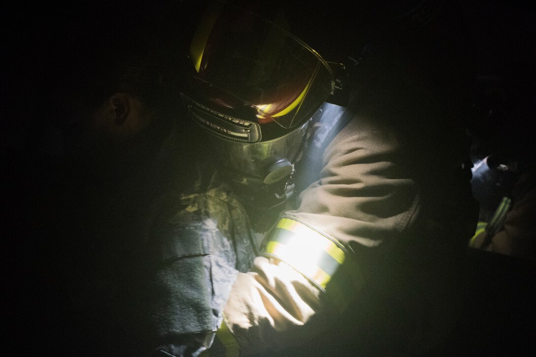 A U.S. Air Force firefighter from the 612th Air Base Squadron carries a simulated burn victim from a smoke-filled building during a joint training exercise, June 26, 2019, at Soto Cano Air Base, Honduras. Members from Joint Task Force – Bravo’s Medical Element, 612th Air Base Squadron firefighters and 480th Military Police Company worked together to accomplish goals during the training event. The event involved the firefighters entering a smoke-filled building to recover burn casualties while the Medical Element performed triage at the scene. The 480TH MPC members provided a cordon of the area and kept rioting personnel from entering the scene. (U.S. Air Force photo by Staff Sgt. Eric Summers Jr.)