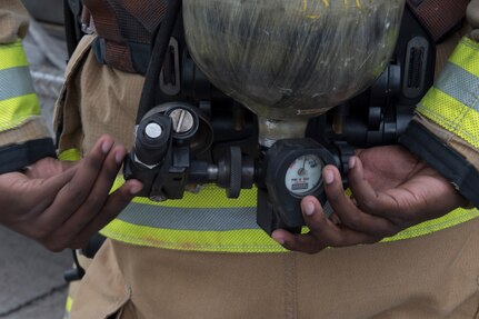 A U.S. Air Force firefighter from the 612th Air Base Squadron adjusts valves on his oxygen tank before entering a smoke-filled building during a joint training exercise June 26, 2019, at Soto Cano Air Base, Honduras. Members from Joint Task Force – Bravo’s Medical Element, 612th Air Base Squadron firefighters and 480th Military Police Company worked together to accomplish goals during the training event. The event involved the firefighters entering a smoke-filled building to recover burn casualties while the Medical Element performed triage at the scene. The 480TH MPC members provided a cordon of the area and kept rioting personnel from entering the scene. (U.S. Air Force photo by Staff Sgt. Eric Summers Jr.)