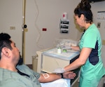 Danielle Gonzales and Ric Torres, nuclear medicine technologists, demonstrate how the lutetium Lu 177 dotatate is administered to a patient in the Nuclear Medicine Department at Brooke Army Medical Center June 27. Nuclear medicine technologists are specially trained to administer radiopharmaceutical to patients.