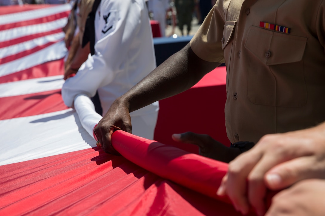 U.S. service members unfurl the United States flag during a Memorial Day ceremony at the Intrepid Sea, Air, and Space Museum as part of Fleet Week New York in New York City NY, May 27, 2019. Memorial Day honors the fallen men and women of the U.S. Armed Forces. Fleet Week NY is an opportunity for the American public to meet their Marine Corps, Navy, and Coast Guard service members and experience America’s sea services firsthand.