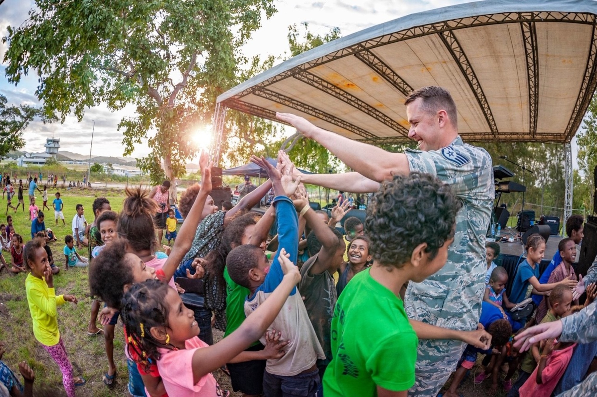 Staff Sgt Bryan Andrews gives high-fives to young audience members in Papua New Guinea at a performance for members of the Papua New Guinea Defence Force Air Transport Wing and their families.