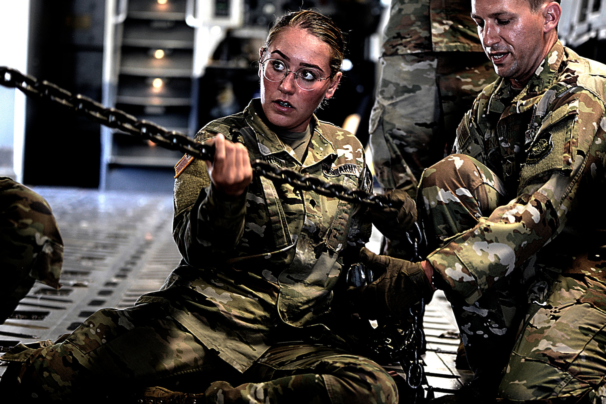 U.S. Air Force Master Sgt. Collin Cenci, 305th Air Mobility Wing loadmaster, instructs U.S. Army Spc. Christina Leighmanuell, 3rd Battalion, 321st Field Artillery Regiment launcher-driver, how to tie down a High Mobility Artillery Rocket System inside  a C-17 Globemaster III, at Pope Army Airfield, North Carolina, June 25, 2019. Aircrew from Joint Base McGuire-Dix-Lakehurst, New Jersey, and Soldiers from Ft. Bragg, North Carolina, conducted a joint-force HIMARS Rapid Infiltration training exercise to efficiently perform precision long-range, total-force operations.