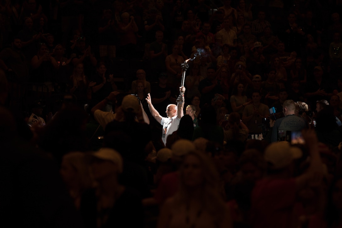 A competitor carries the symbolic torch during the opening ceremony at Amalie Arena in Tampa, Florida, June 23, 2019, during the 2019 Department of Defense Warrior Games. The DoD Warrior Games are conducted June 21-30, hosted by Special Operations Command, Tampa, Florida. It is an adaptive sports competiton for wounded, ill, and injured service members and veterans. Approximately 300 athletes, representing teams from the Army, Marine Corps, Navy, Air Force, Special Operations Command, United Kingdom Armed Forces, Australian Defense Force, Canadian Armed Forces, Armed Forces of the Netherlands, and the Danish Armed Forces will compete in archery, cycling, shooting, sitting volleyball, swimming, track, field, wheelchair basketball, indoor rowing, and powerlifting.