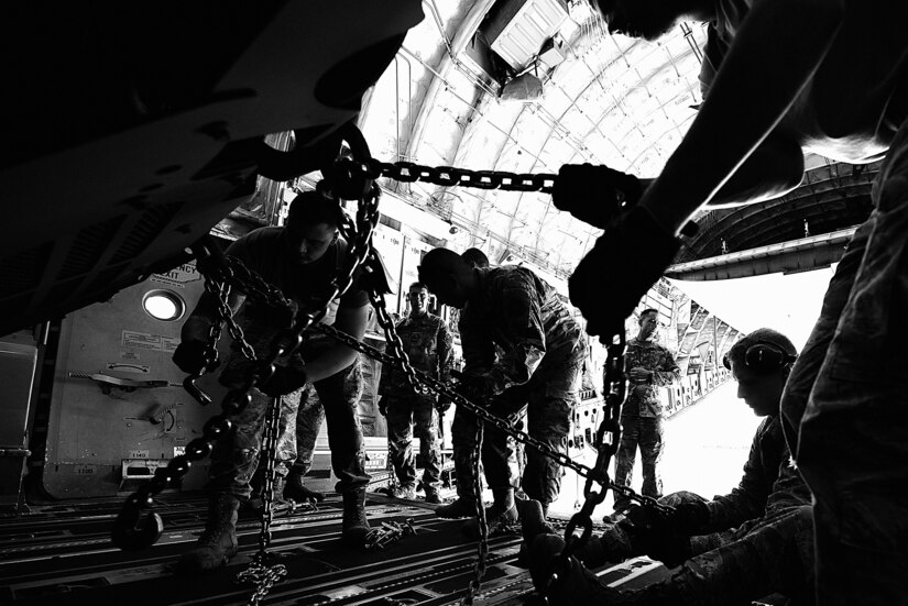 U.S. Air Force Airmen from the 305th Air Mobility Wing at Joint Base McGuire-Dix-Lakehurst, New Jersey, and U.S. Army Soldiers from the 3rd Battalion, 321st Field Artillery Regiment at Ft. Bragg, North Carolina, tie down a High Mobility Artillery Rocket System inside of a C-17 Globemaster III during a joint-training HIMARS Rapid Infiltration exercise at Pope Army Airfield, North Carolina, June 25, 2019. The combination of rapid global mobility and agile ground artillery produces precision long-range mission execution.