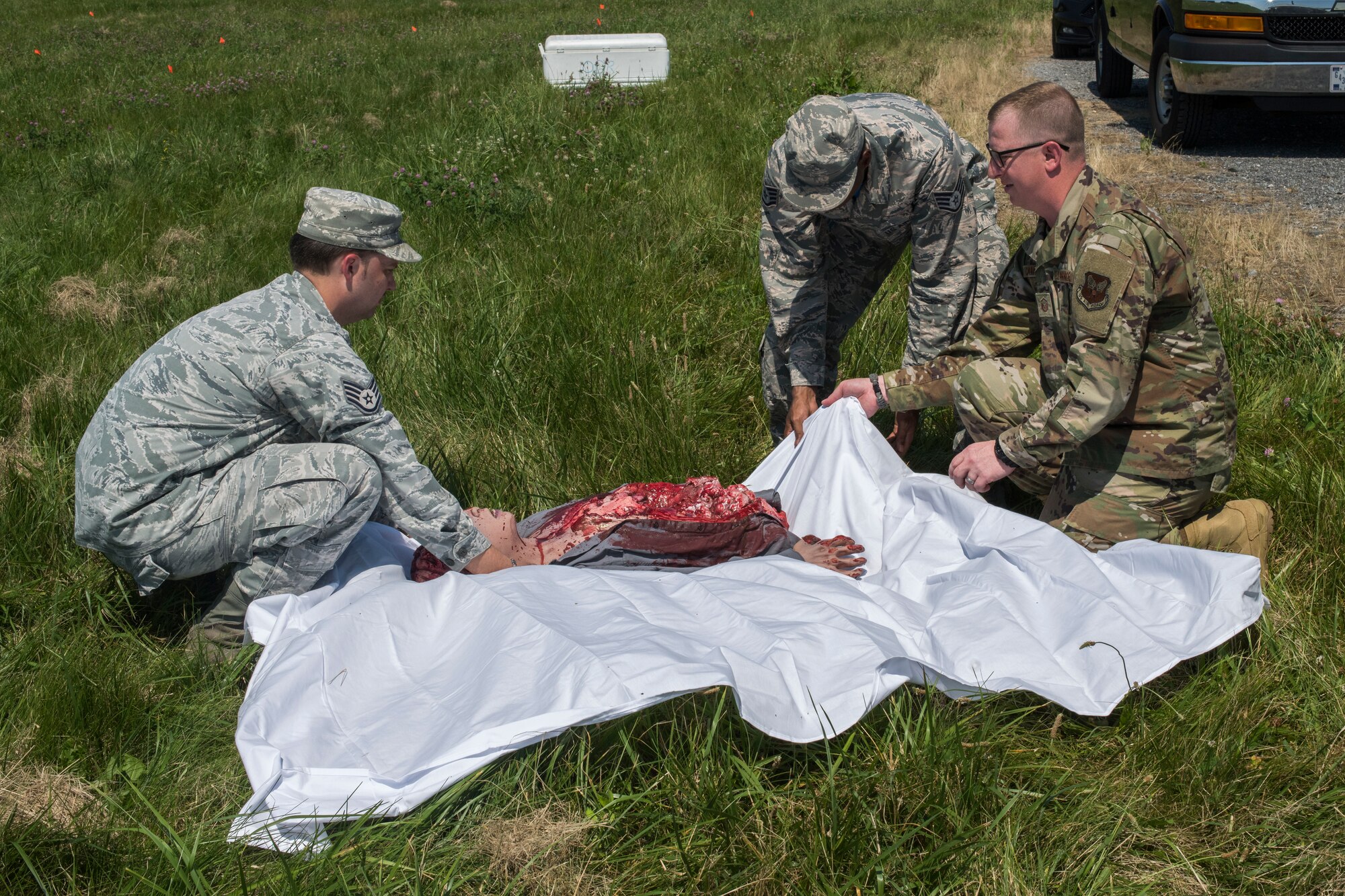 Air Force Mortuary Affairs Operations and 436th Force Support Squadron members wrap a training dummy during a search-and-recovery exercise June 28, 2019, at Dover Air Force Base, Del. The three members demonstrated how to properly tag and preserve remains during an aircraft mishap. (U.S. Air Force photo by Senior Airman Christopher Quail)