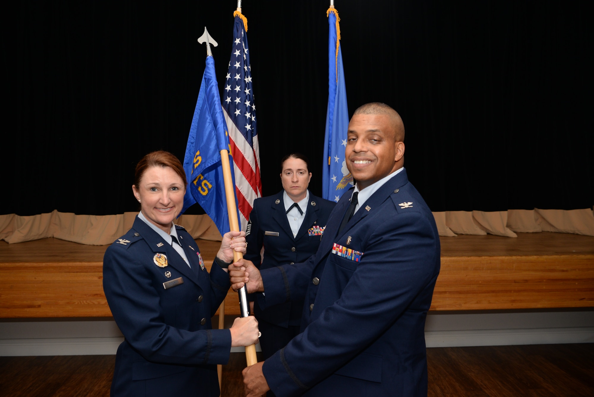 U.S. Air Force Col. Beatrice Dolihite, 81st Medical Group commander, passes the guidon to Col. Trent Tate, incoming 81st Diagnostics and Therapeutics Squadron commander, during a change of command ceremony inside the Don Wylie Auditorium on Keesler Air Force Base, Mississippi, June 27, 2019. The passing of the guidon is a ceremonial symbol of exchanging command from one commander to another. (U.S. Air Force photo by Airman 1st Class Spencer Tobler)