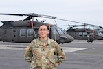 U.S. Army Spc. Courtney Petrauskas, information technology specialist with Headquarters and Headquarters Company, 28th Expeditionary Combat Aviation Brigade, poses for a photo in front of UH-60 Black Hawk helicopters at Muir Army Airfield.