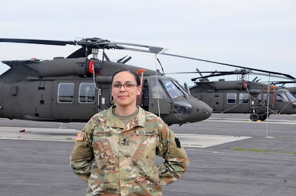 U.S. Army Spc. Courtney Petrauskas, information technology specialist with Headquarters and Headquarters Company, 28th Expeditionary Combat Aviation Brigade, poses for a photo in front of UH-60 Black Hawk helicopters at Muir Army Airfield.