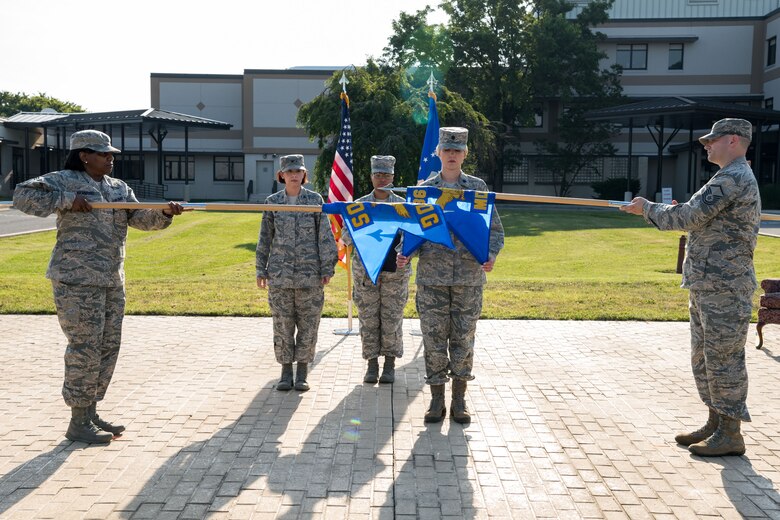 Col. Patricia Fowler, 436th Medical Group commander, watches Lt. Col. Lisa Palmer, 436th Medical Operations Squadron commander, furl the 436th MDOS guidon held by Master Sgt. Chad Boley, 436th MDOS superintendent, during a redesignation ceremony June 28, 2019, at the 436th MDG on Dover Air Force Base, Del. Chief Master Sgt. Cynthia Hammond, 436th MDG superintendent, unfurls the guidon of the newly designated 436th Health Care Operations Squadron. (U.S. Air Force photo by Roland Balik)