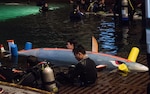 CTC Engineers divers from the Frederick County Career and Technology Center (FCCTC) in Maryland sit with their submarine, CLS Mako, as they await their final run in the David Taylor Model Basin at the 15th International Submarine Races on June 28 at Naval Surface Warfare Center, Carderock Division (NSWCCD) in West Bethesda, Md.