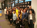 Group of people pose in front of National Basketball League banner.