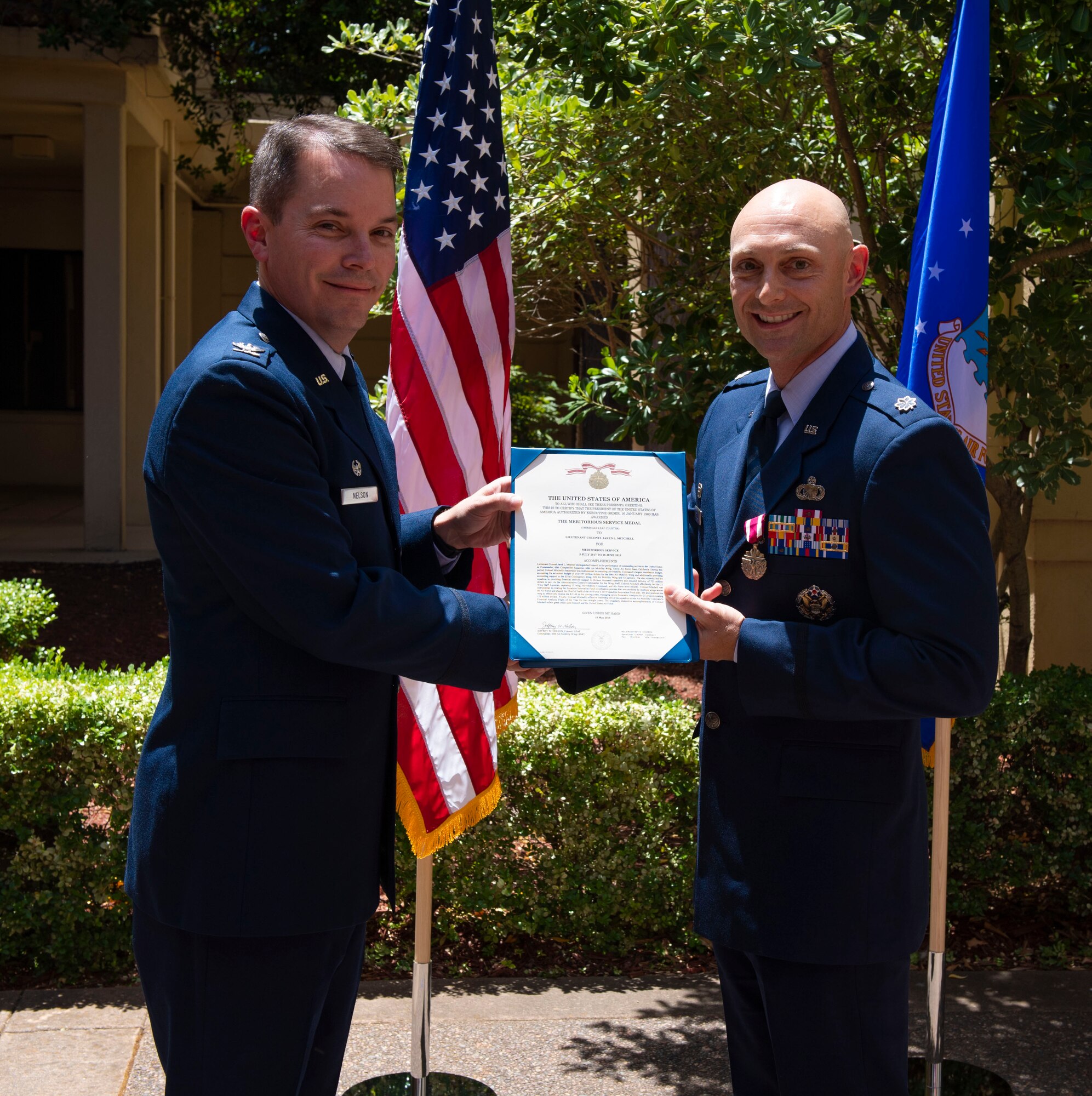 U.S. Air Force Col. Jeff Nelson, left, 60th Air Mobility Wing commander, presents Lt. Col. Jared Mitchell, 60th Comptroller Squadron outgoing commander, with a meritorious service medal during a change of command ceremony June 28, 2019, at Travis Air Force Base, California. During the ceremony, Mitchell passed the reign of command to Maj. Andrew Wilkins. (U.S. Air Force photo by Airman 1st Class Jonathon Carnell)