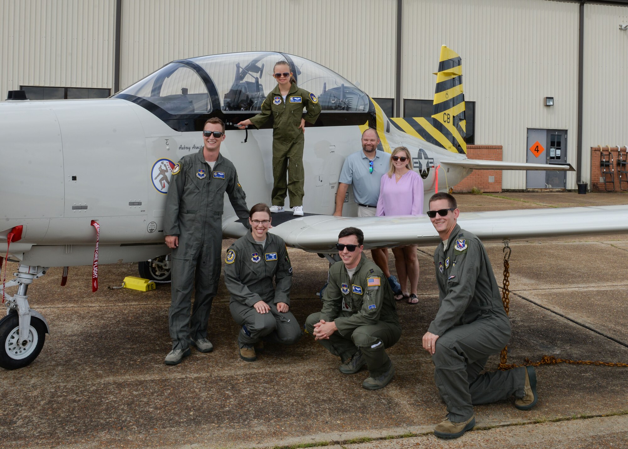 Aubrey Armstrong, her parents and pilots from the 41st Flying Training Squadron stand in front of a T-6 Texan II June 25, 2019, on Columbus Air Force Base, Miss. Aubrey spent the day with the pilots and, she got her own flight suit. (U.S. Air Force photo by Airman Davis Donaldson)