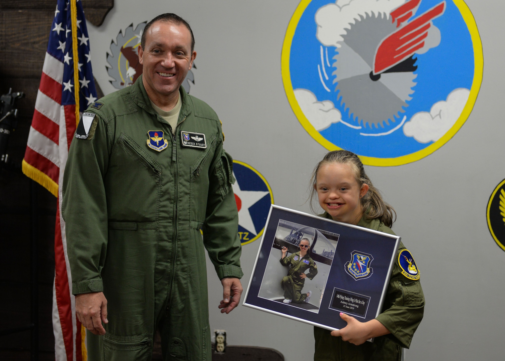 Col. Derek Stuart, 14th Operations Group commander, gives Aubrey Armstrong, a Pilot for a Day, a plaque with her picture June 25, 2019, at Columbus Air Force Base, Miss. Aubrey received various coins, unit patches and awards throughout the day. (U.S. Air Force photo by Airman Davis Donaldson)