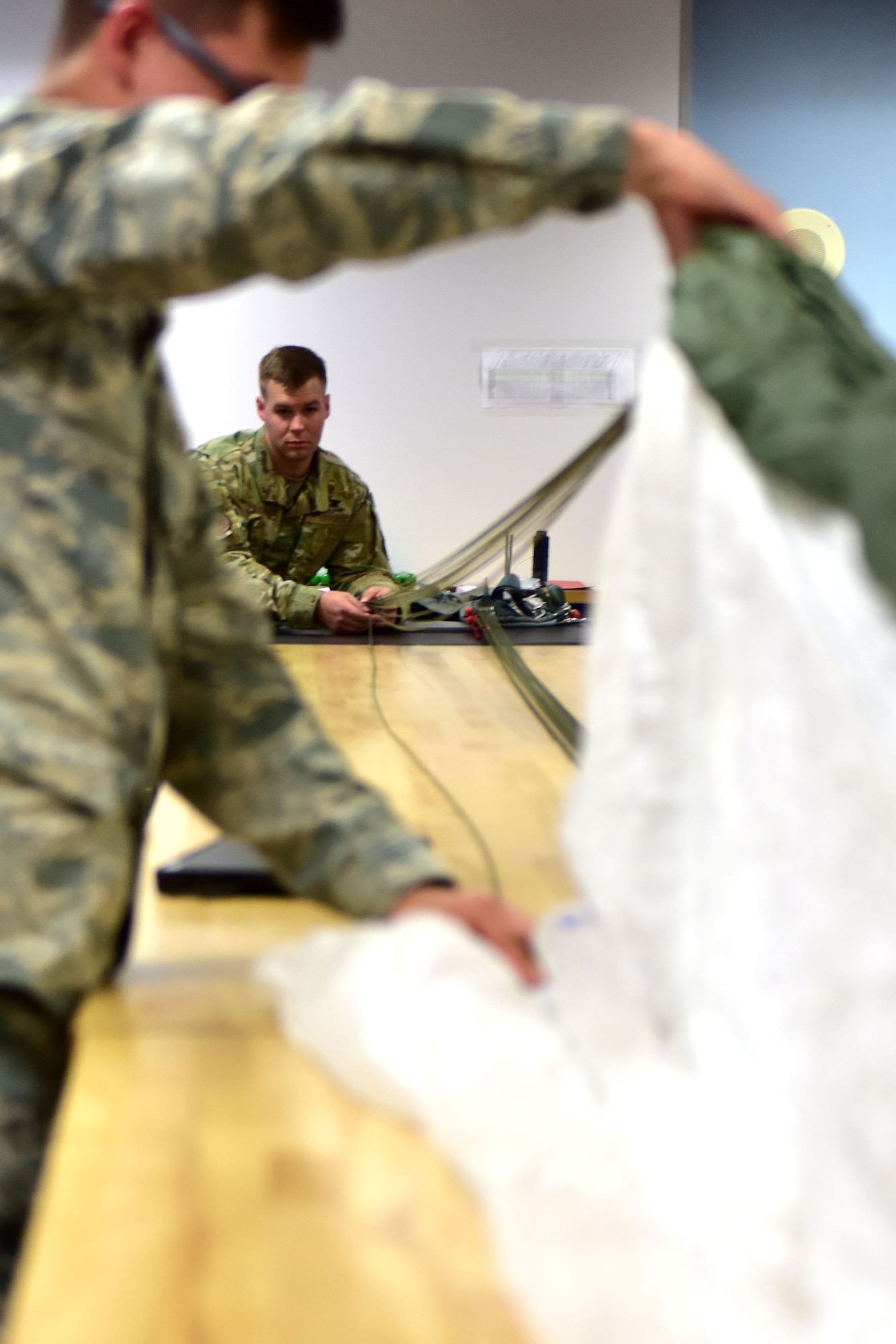 Two Airmen fold a parachute.