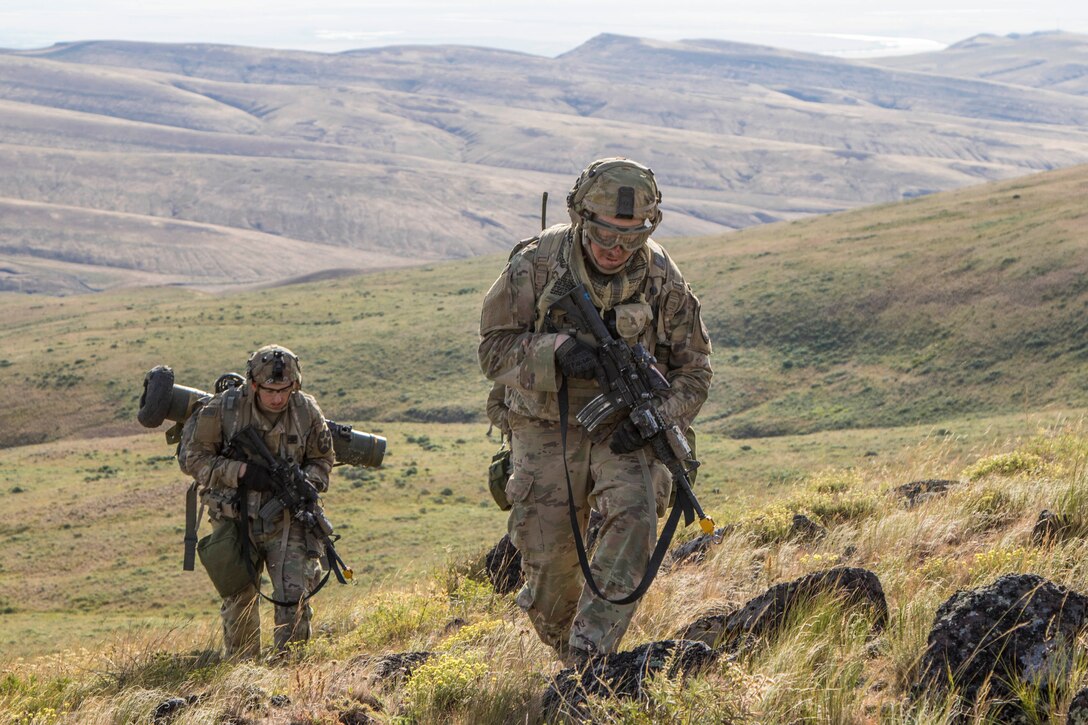 Two soldiers walk through a field.