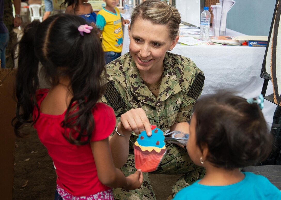 A military person plays with children.