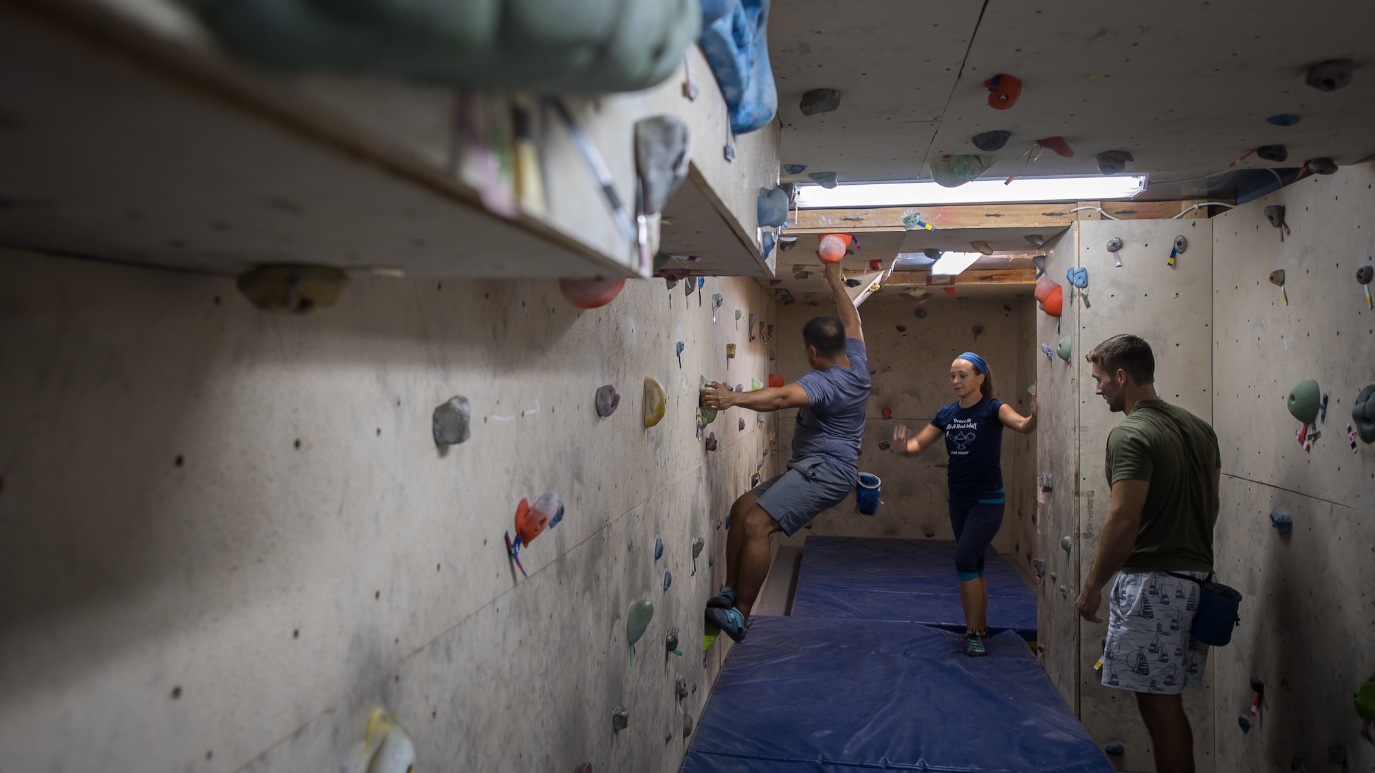 U.S. Air Force Maj. Breanna Gawrys (center), 386th Expeditionary Medical Group physician, and 1st Lt. Luke Russell (right), 386th EMDG physician’s assistant, help guide a gym patron as he climbs the bouldering wall near the Flex Gym on Ali Al Salem Air Base, Kuwait, June 30, 2019. Gawrys and Russell worked together to renovate the wall and provide an additional fitness option for ASAB personnel. (U.S. Air Force photo by Tech. Sgt. Daniel Martinez)