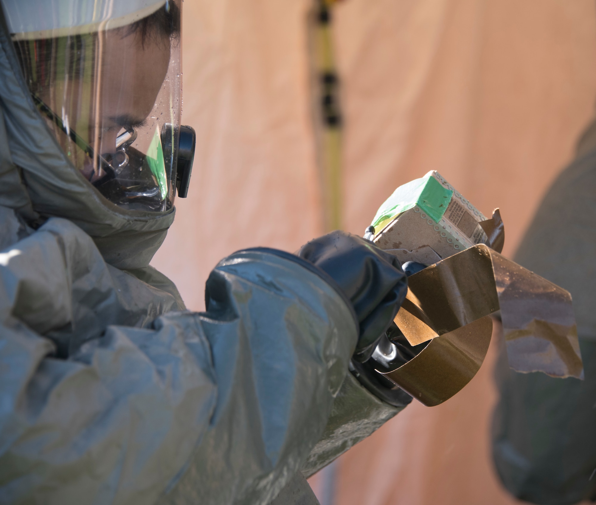 A U.S. Airman cuts simulated chemical detection tape June 27, 2019, at Travis Air Force Base, California. The tape was part of a hazardous material exercise at David Grant USAF Medical Center. (U.S. Air Force photo by Staff Sgt. Amber Carter)