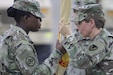 Colonel Mary O.B. Drayton, left, incoming commander, 408th Contracting Support Brigade, accepts the unit colors from Col. Christine A. Beeler, deputy to the commanding general for outside the continental United States for Army Contracting Command, during the change of command ceremony June 27, 2019, at Camp Arifjan, Kuwait. This is Drayton’s third assignment within the 408th CSB.