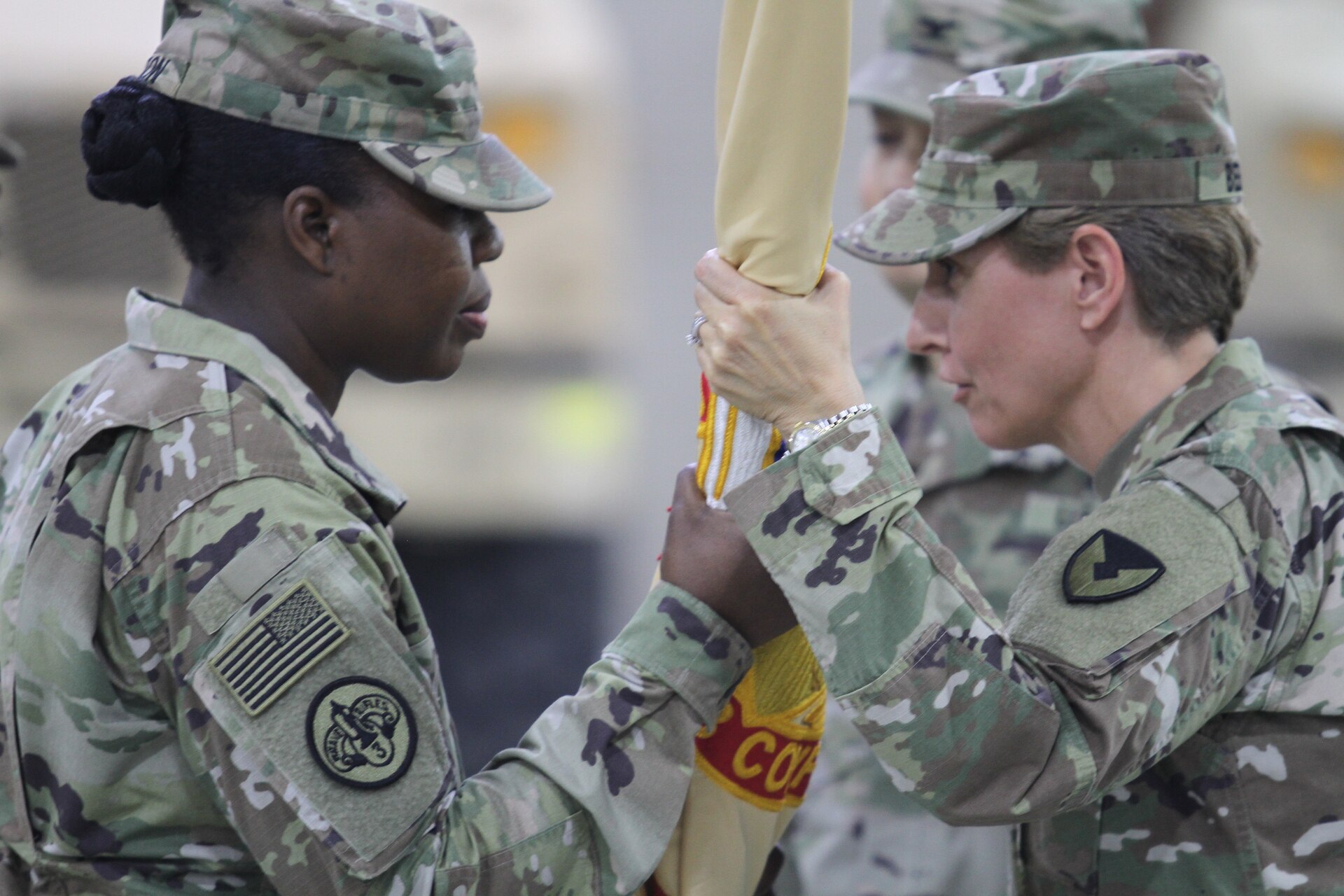 Colonel Mary O.B. Drayton, left, incoming commander, 408th Contracting Support Brigade, accepts the unit colors from Col. Christine A. Beeler, deputy to the commanding general for outside the continental United States for Army Contracting Command, during the change of command ceremony June 27, 2019, at Camp Arifjan, Kuwait. This is Drayton’s third assignment within the 408th CSB.